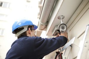 Man Installing Security Camera With Blue Safety Helmet On