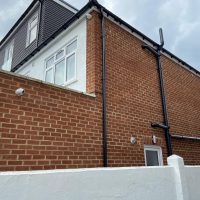 Side view of house with security camera on brick wall