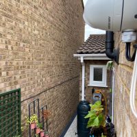 Closeup of white Hikvision CCTV camera on side of house in Royston