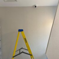 Newly installed white cctv camera with yellow ladder in foreground